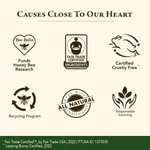 A beige promotional graphic with the heading 'CAUSES CLOSE TO OUR HEART' and six dark brown icon/label elements for honey bee research, fair trade certified ingredients, cruelty free status, recycling program, all natural ingredients, and responsible sourcing. A green footer contains certification text.